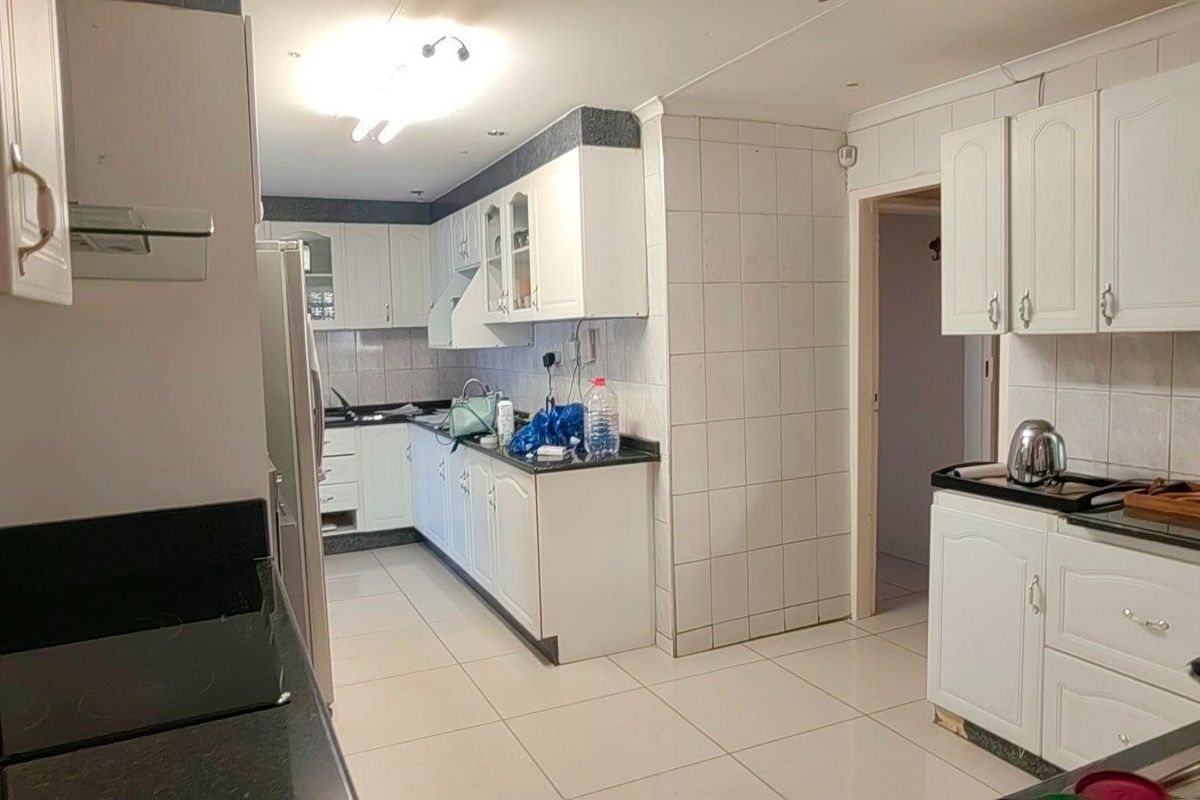 A functional kitchen featuring white cabinetry, dark granite countertops, tiled flooring, and a tiled backsplash, offering a practical layout for daily meal preparation.