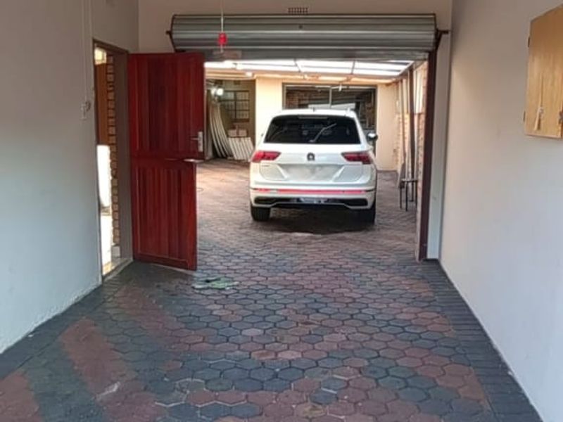 A functional garage space featuring paved flooring, an automated door mechanism, and a side access door leading to the exterior.