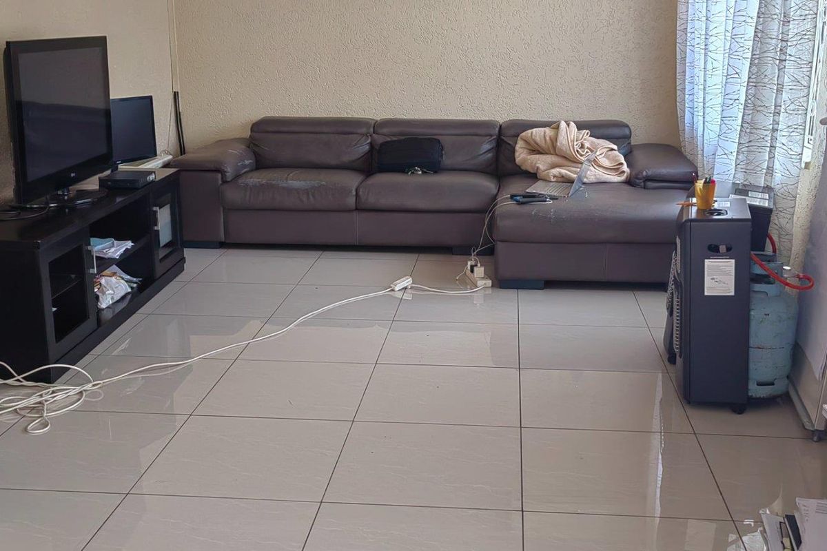 A living room featuring large format floor tiles and textured wall finishes, providing a neutral base for potential interior updates.