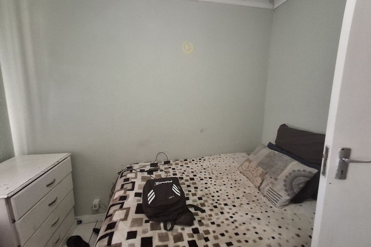 A compact bedroom featuring tiled flooring and neutral wall finishes, providing a functional space for rest.
