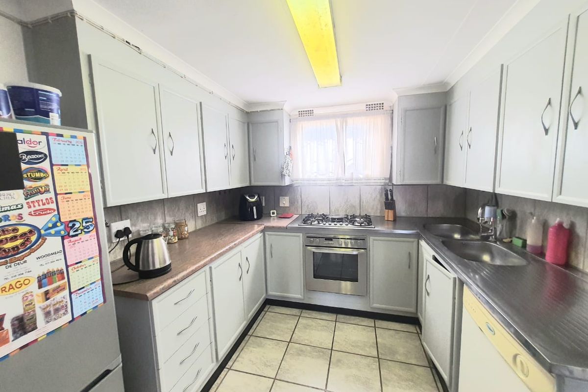 Functional kitchen featuring built-in cabinetry, stainless steel sink, gas hob, and oven, with tiled flooring and ample counter space.