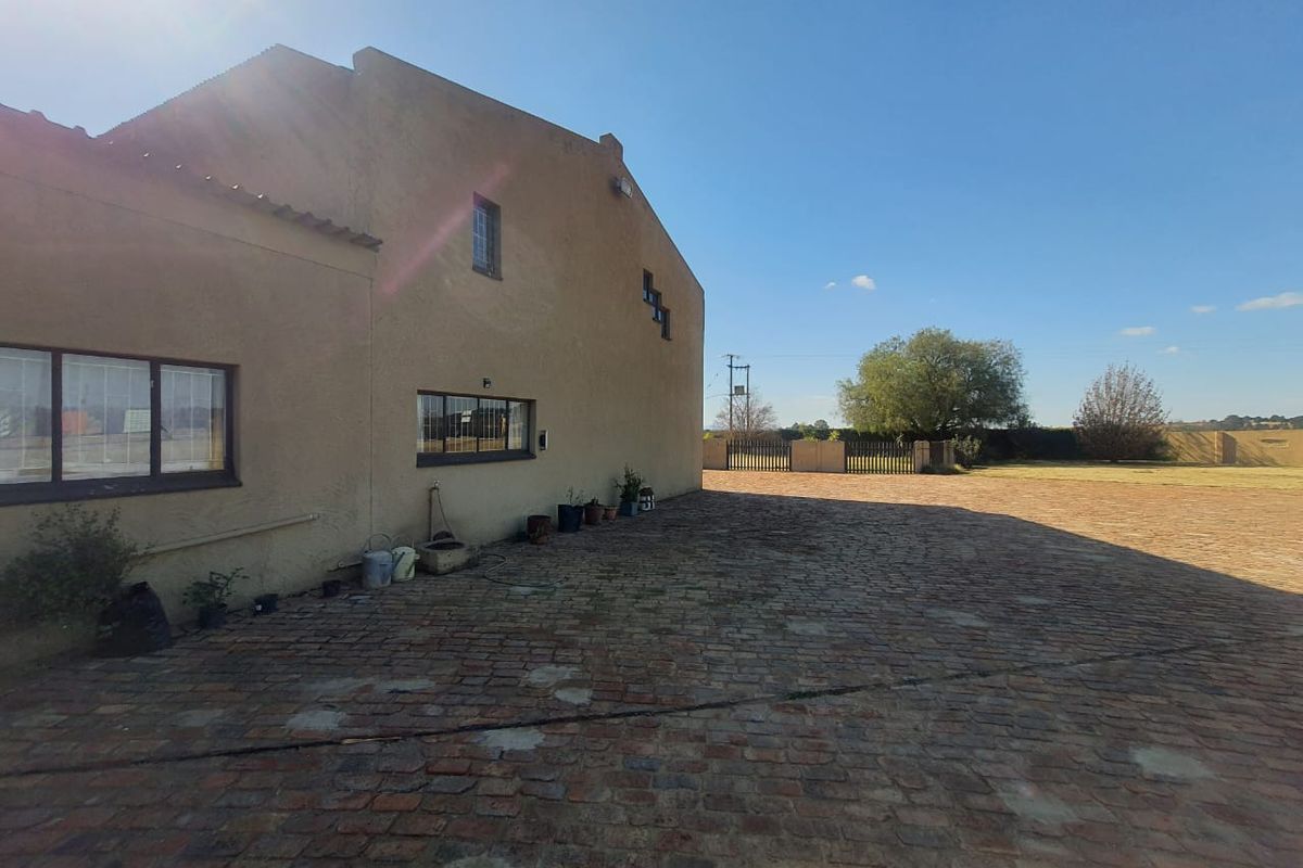 A view of the side exterior of the property featuring a large brick-paved courtyard area and a solid masonry building structure.