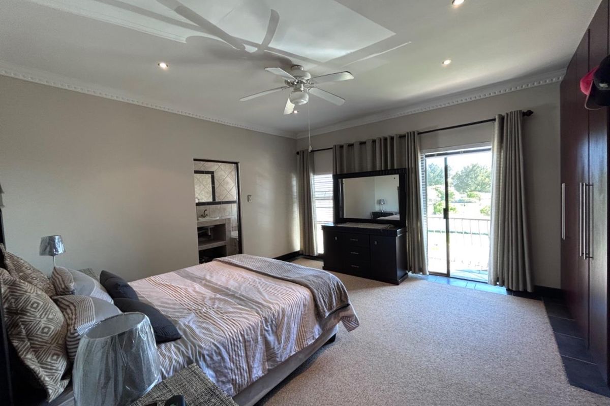 Spacious bedroom featuring recessed ceiling lighting, a ceiling fan, built-in cupboards, and direct access to a private balcony through sliding glass doors.