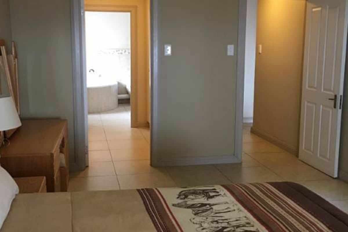 A bedroom featuring tiled flooring and direct access to an adjoining bathroom, showcasing a functional layout with neutral wall finishes.