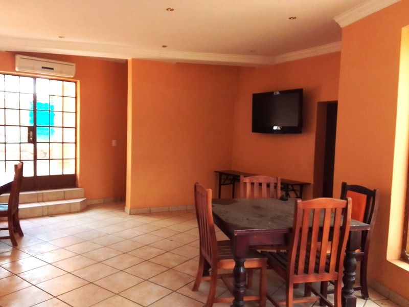A living area featuring tiled flooring, recessed lighting, and a wall-mounted air conditioning unit with access to an outdoor area via a glass door.