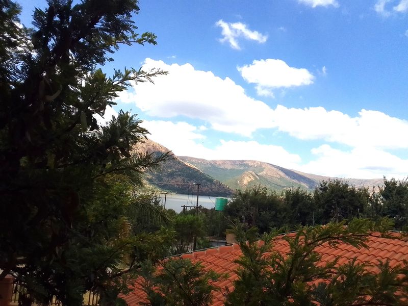 A scenic view overlooking a lake and mountain range, featuring a tiled roof in the foreground.