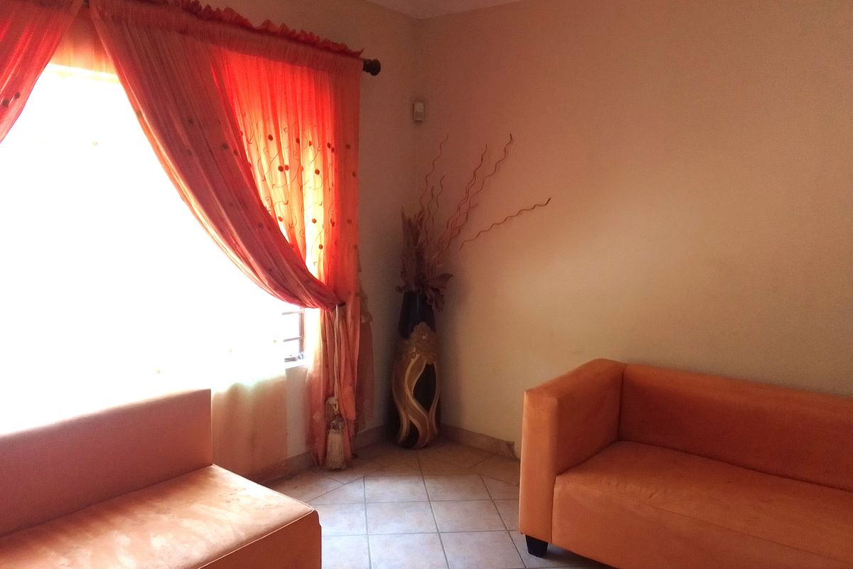 A living room area featuring tiled flooring and a window with natural light.