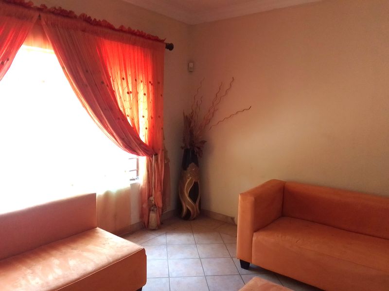 A living room area featuring tiled flooring and a window with natural light.