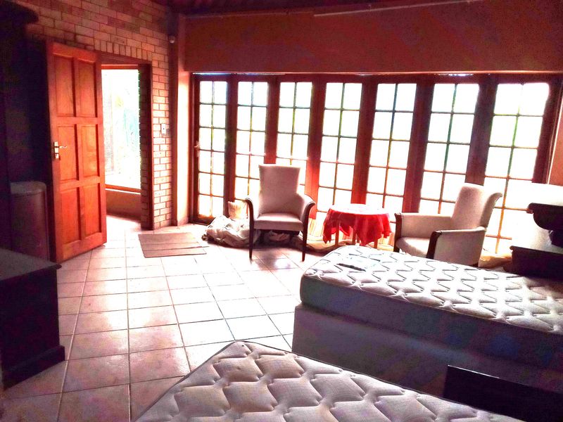 A living area featuring exposed brick walls, tiled flooring, and large multi-pane windows that provide natural light.