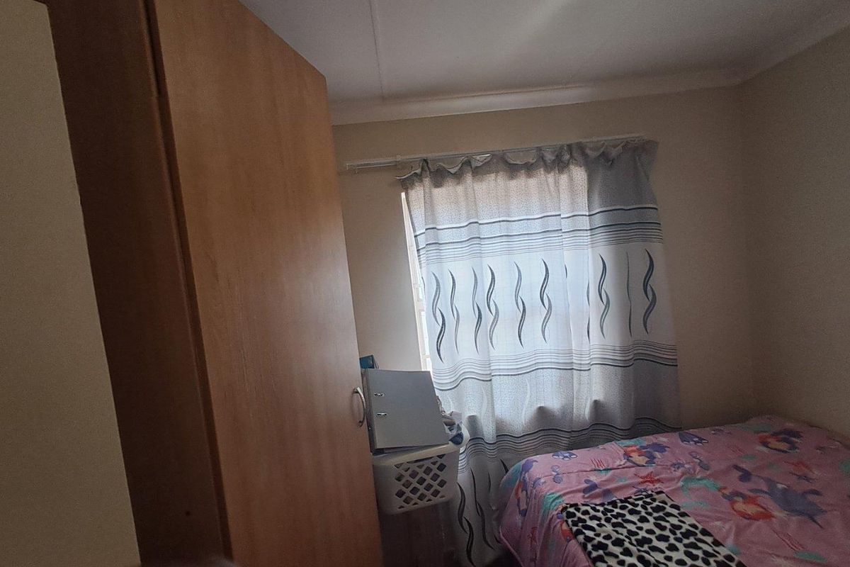 A standard bedroom featuring built-in wooden cabinetry and a window with curtain treatments.