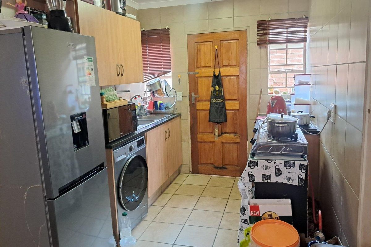 A functional galley-style kitchen featuring tiled flooring, built-in cabinetry, and a dedicated space for laundry appliances.