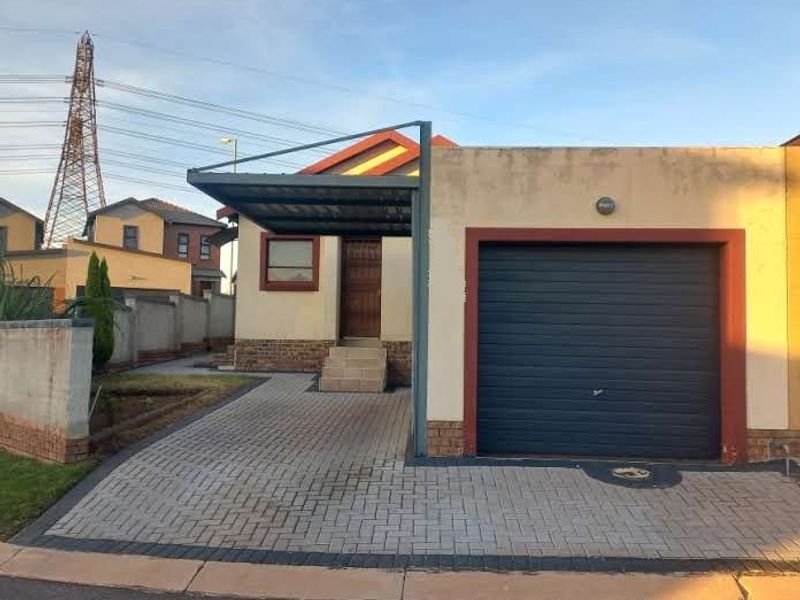 Front exterior view of the property featuring a paved driveway, a covered carport, and a single garage with a roller door.