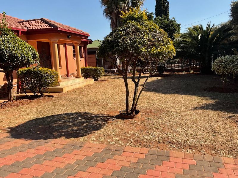 Front view of a residential house featuring a tiled roof, decorative porch columns, and a paved driveway leading to a landscaped front garden.