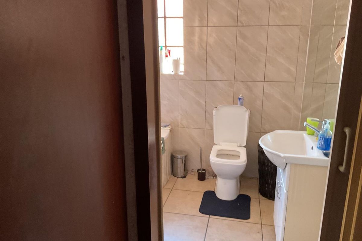 A functional bathroom featuring tiled walls and flooring, equipped with a standard toilet, pedestal basin, and bathtub.
