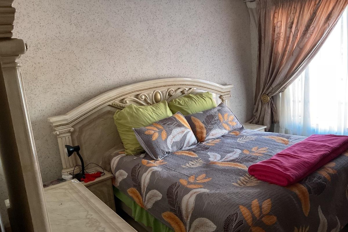 A bedroom featuring textured wallpaper and window treatments, offering a functional space with potential for modern updates.