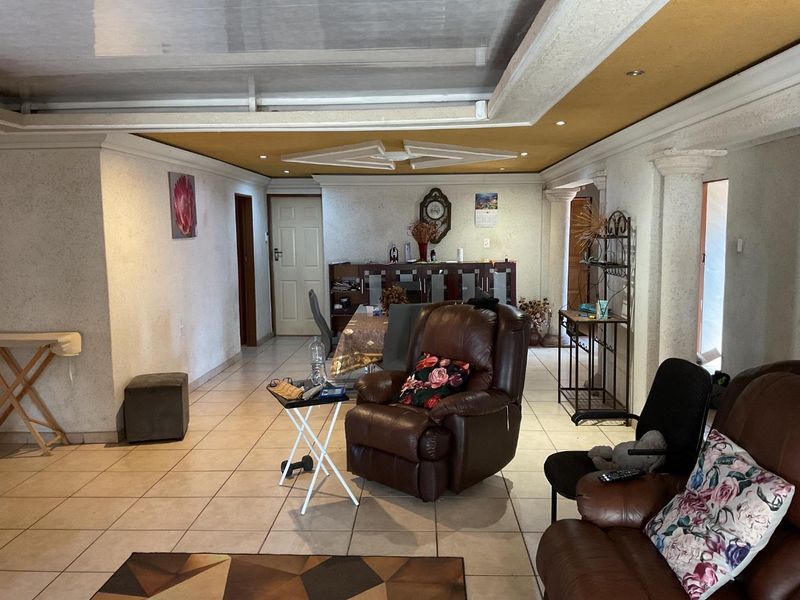 Spacious living area featuring tiled flooring, decorative columns, and a unique recessed ceiling design with integrated lighting.