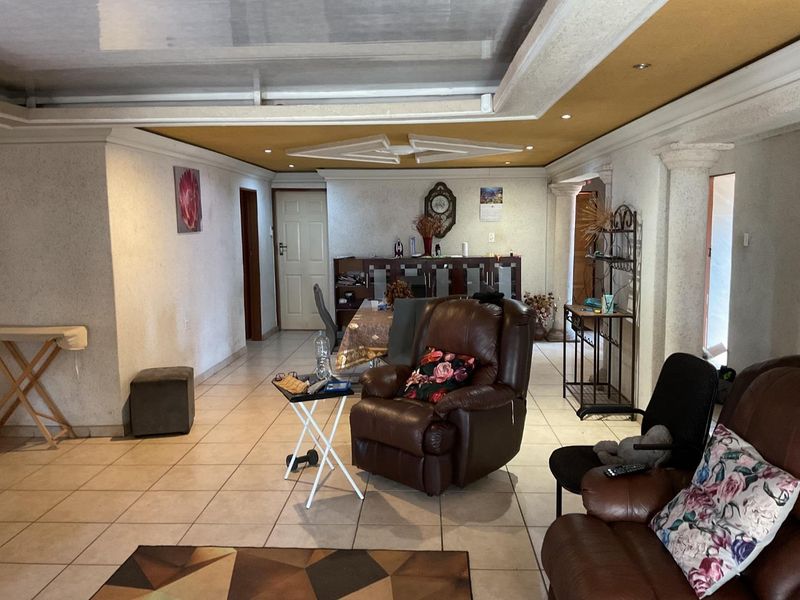 Spacious living area featuring tiled flooring and a decorative recessed ceiling with integrated lighting, offering a versatile layout for family living.