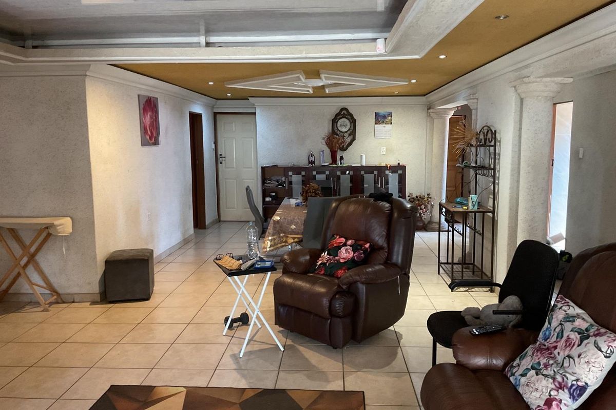 Spacious living area featuring tiled flooring, decorative ceiling details with recessed lighting, and architectural columns, offering a versatile layout for family living.