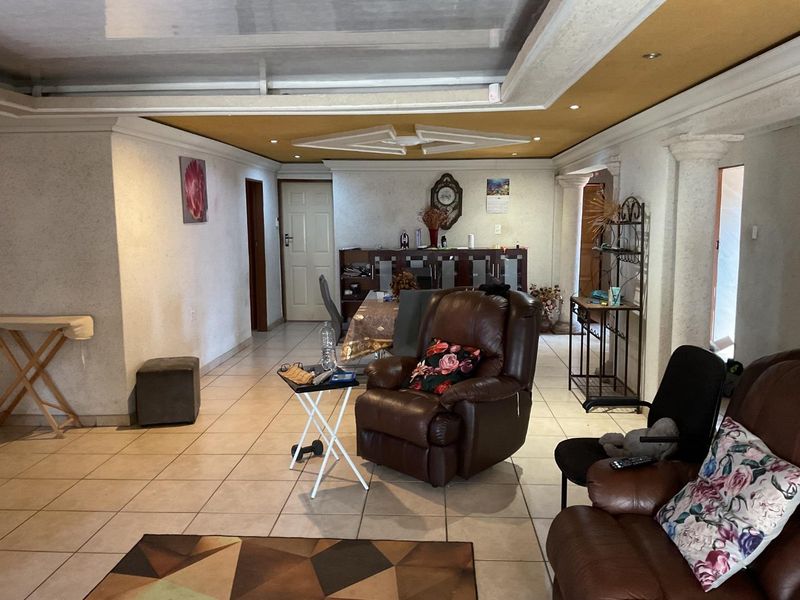Spacious living area featuring tiled flooring, decorative ceiling details with recessed lighting, and architectural columns, offering a versatile layout for family living.