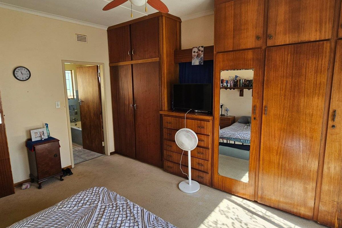 A bedroom featuring extensive built-in wooden cabinetry and an en-suite bathroom access point.
