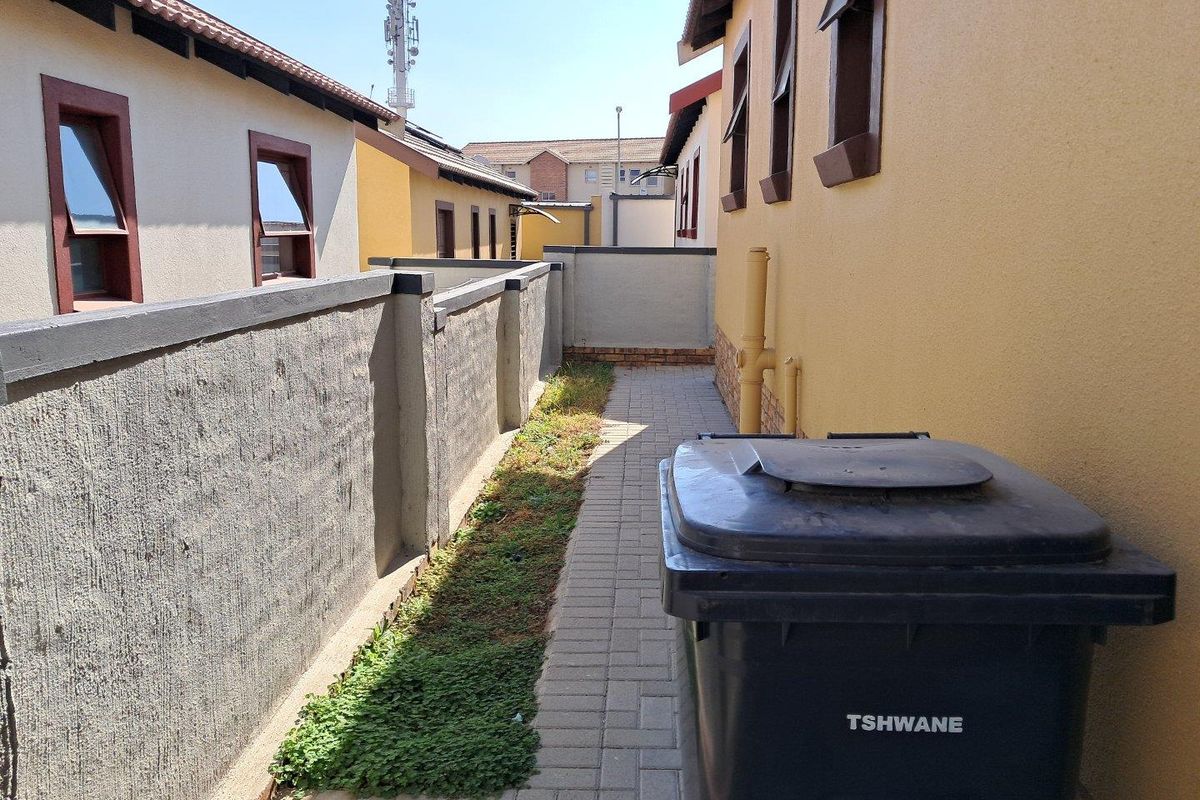 A narrow side passage featuring paved flooring, boundary walling, and exterior building access.