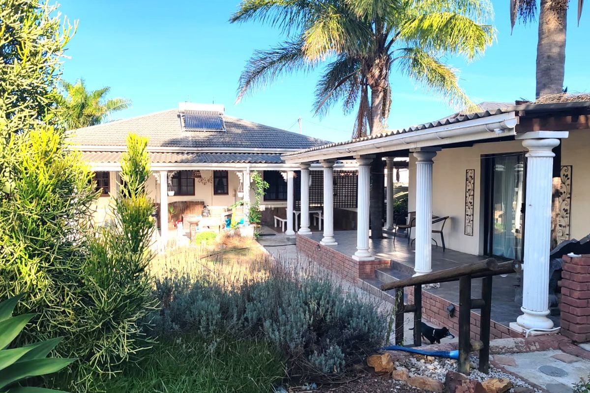 Rear view of the house featuring a covered patio with decorative columns, tiled roof, and integrated solar water heating system.