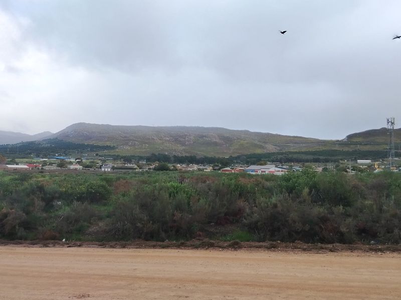 A wide-angle view of the vacant residential land, showcasing the surrounding landscape, natural vegetation, and distant mountain scenery.