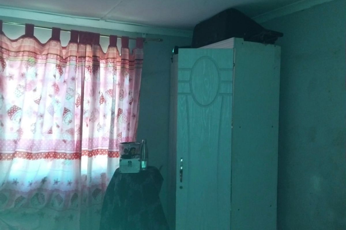 A bedroom featuring basic ceiling tiles and wall finishes, currently utilized with storage furniture.