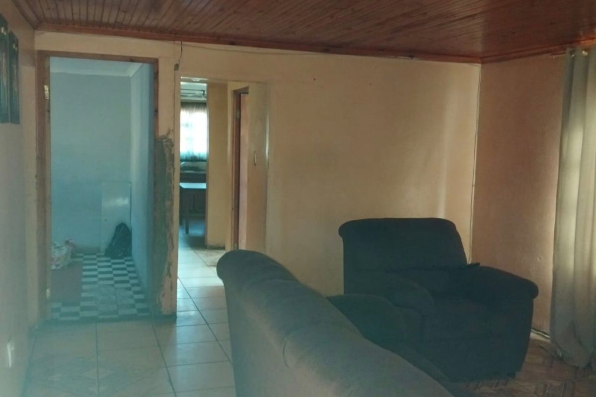 Living room featuring timber ceiling and tiled flooring, showing signs of wear and requiring cosmetic updates to the walls and finishes.