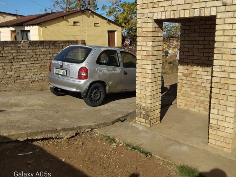 Exterior view of a property featuring a face brick entrance structure and a concrete driveway with visible surface cracking.