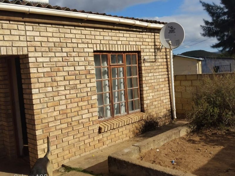Rear exterior view of a face brick house featuring a solar water heater, satellite dish, and a concrete garden planter.