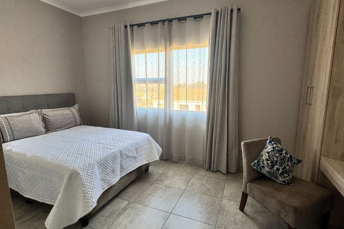 A bedroom featuring tiled flooring, built-in cabinetry, and a window with curtain tracks.