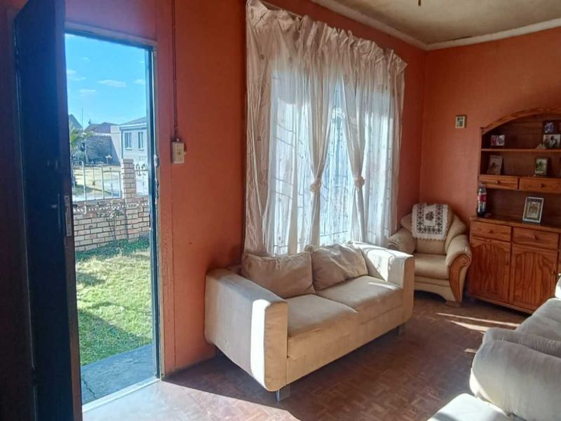 A living room area featuring tiled flooring and direct access to the garden, offering a functional space with potential for cosmetic updates.