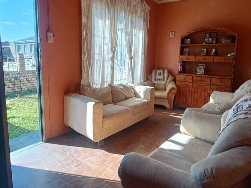 A living room featuring parquet flooring and direct access to the garden through a sliding glass door.