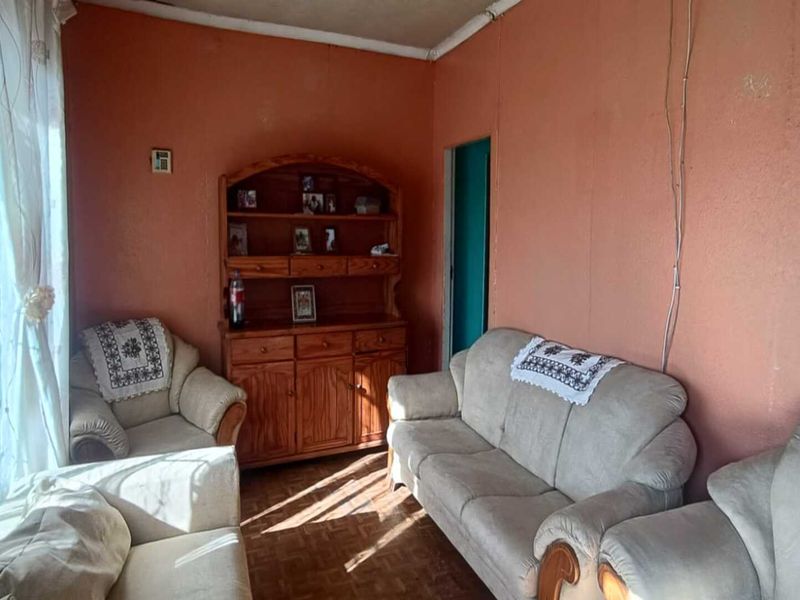 A living room featuring parquet flooring and coved ceilings, currently requiring cosmetic updates to the wall finishes and electrical cable management.