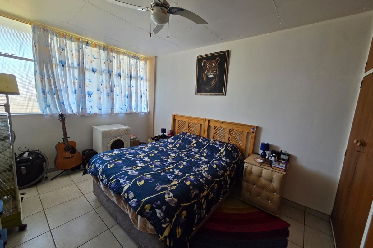 A bedroom featuring tiled flooring, a ceiling fan, and built-in cupboard space.