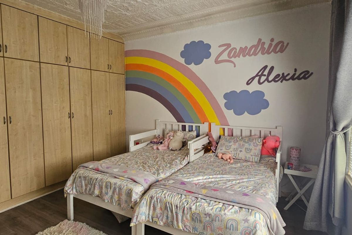 Bedroom featuring built-in wooden cabinetry, laminate flooring, and a window with fitted blinds.