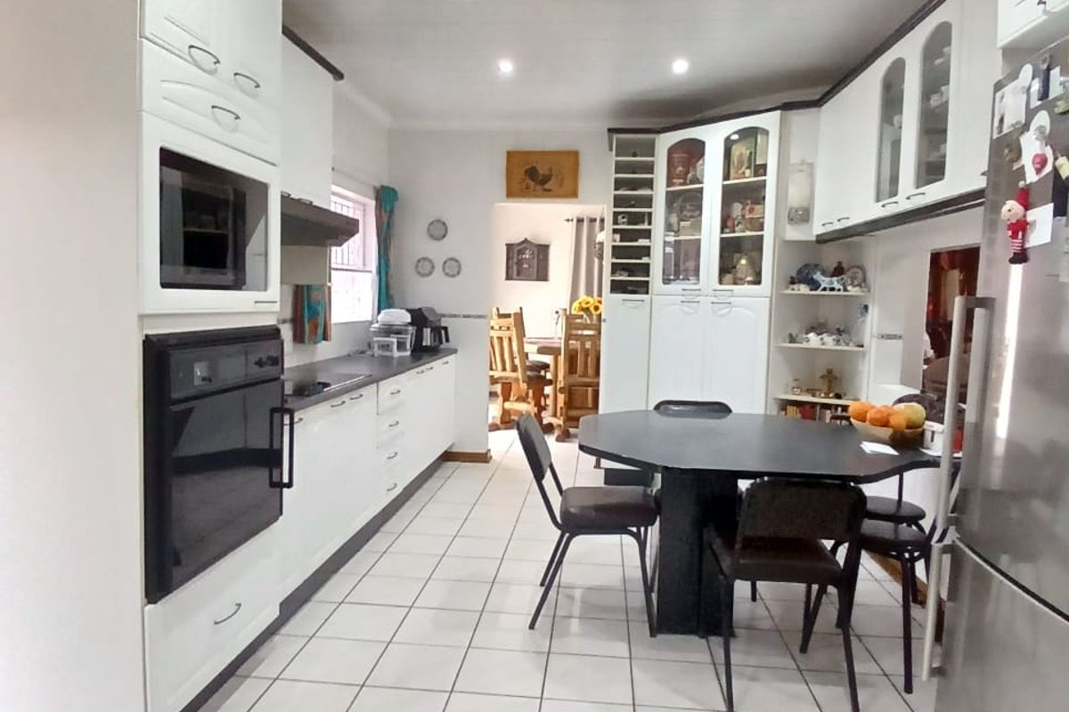 A functional kitchen featuring white cabinetry, built-in oven, integrated microwave, and tiled flooring, offering a practical layout with ample storage space.