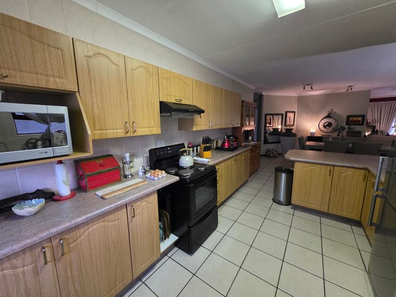 Open plan kitchen featuring laminate cabinetry, tiled flooring, and a breakfast bar, seamlessly flowing into the adjacent dining and living area.