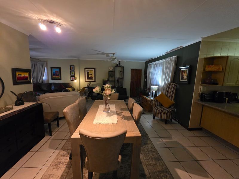 Spacious open-plan living and dining area featuring tiled flooring, a ceiling fan, and an integrated kitchen space with built-in cabinetry.