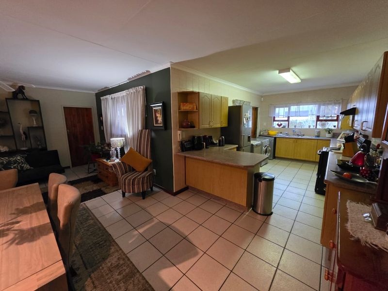Open-plan living and kitchen area featuring tiled flooring, laminate cabinetry, and a functional layout connecting the dining space to the kitchen.