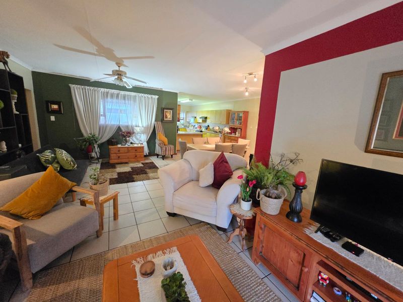Spacious open-plan living and dining area featuring tiled flooring, a ceiling fan, and a connected kitchen with built-in cabinetry.