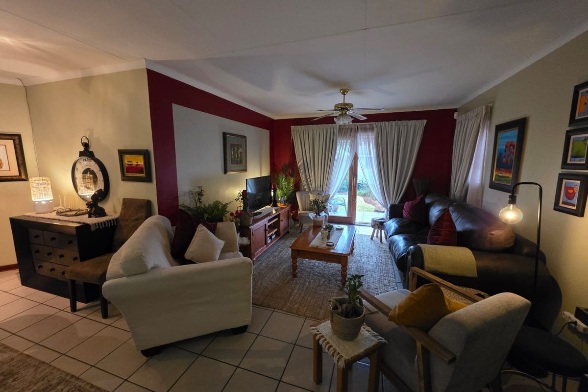 A comfortable living room featuring tiled flooring, a ceiling fan, and a sliding glass door providing access to the outdoor area.