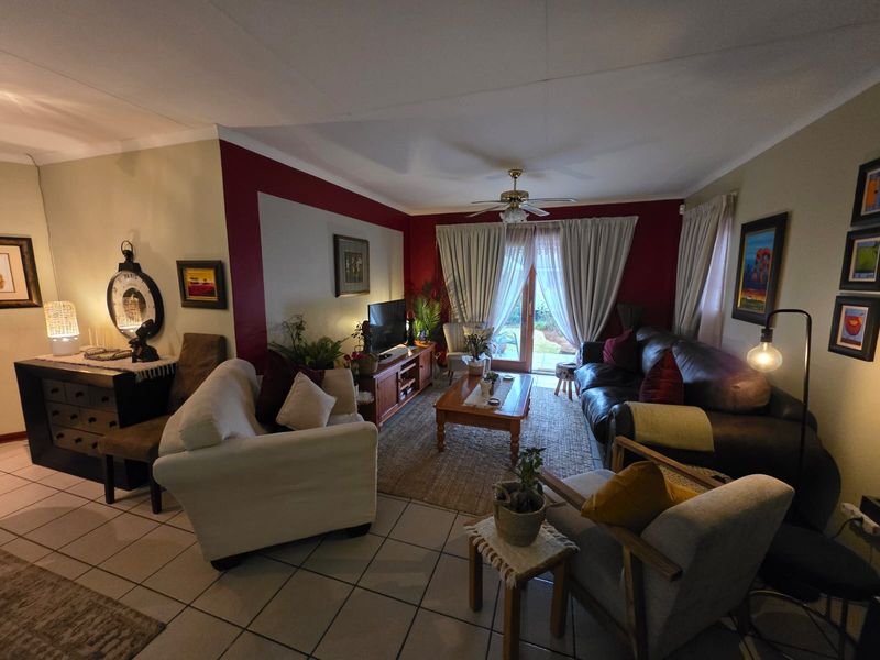 A comfortable living room featuring tiled flooring, a ceiling fan, and a sliding glass door providing access to the outdoor area.