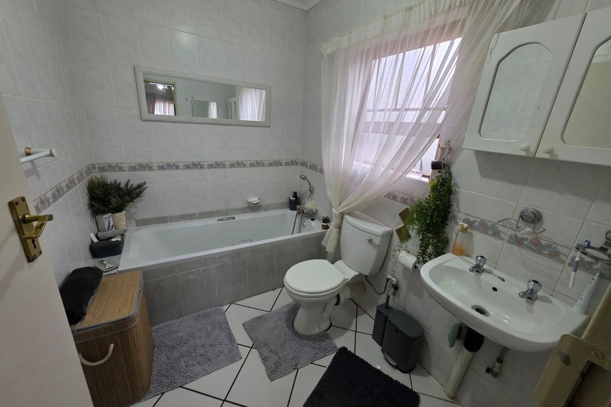 A functional bathroom featuring a built-in bathtub, wall-mounted basin, and toilet, finished with ceramic wall and floor tiles.