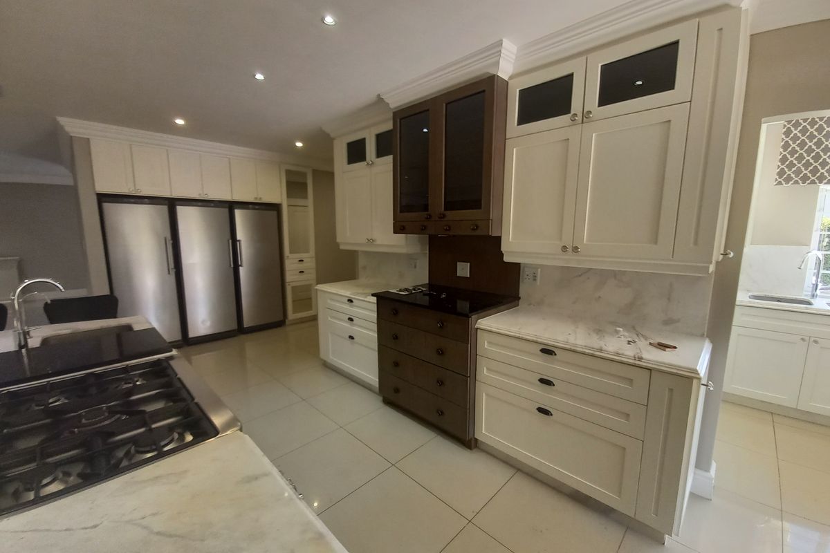 A spacious, modern kitchen featuring high-end cabinetry, marble countertops, integrated appliances, and recessed lighting, offering a clean and functional culinary space.