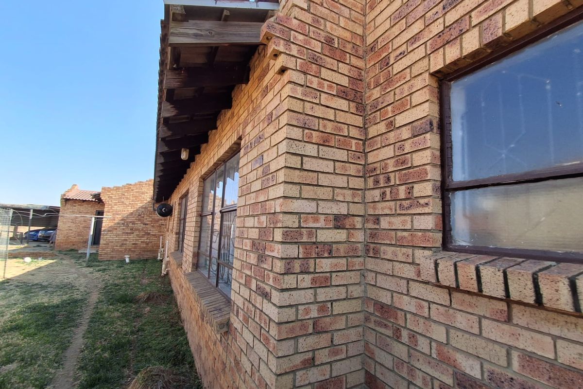 Side exterior view of the house featuring face brick construction, steel-framed windows, and exposed timber eaves.