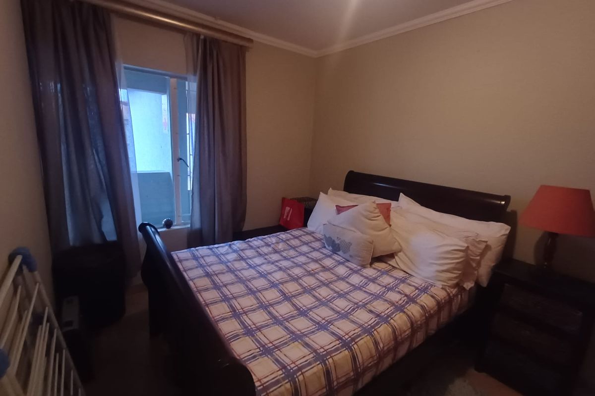 A standard bedroom featuring neutral wall tones, a window with curtain tracks, and crown molding.