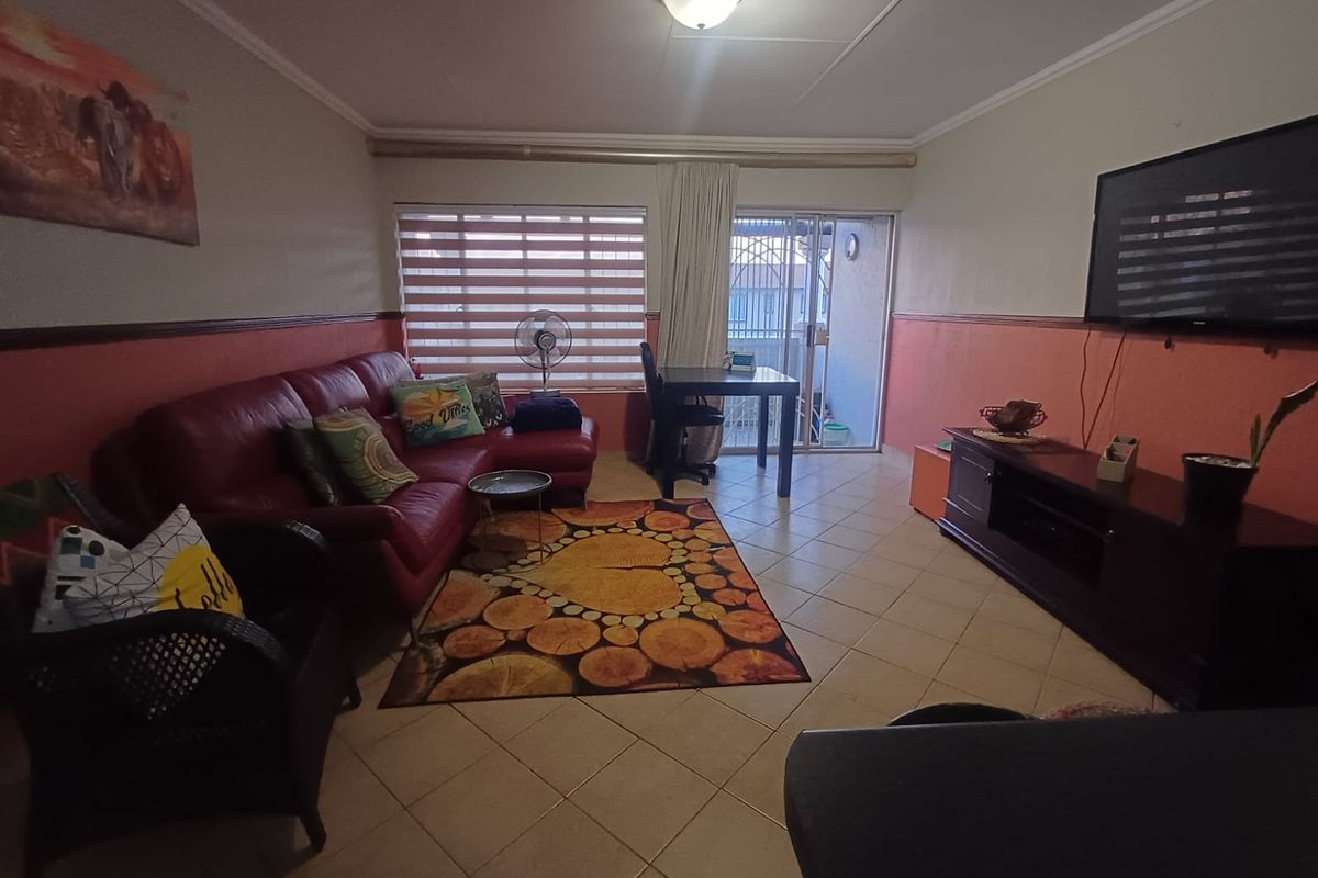 A living room featuring tiled flooring, sliding glass doors leading to an outdoor area, and wall-mounted television space.