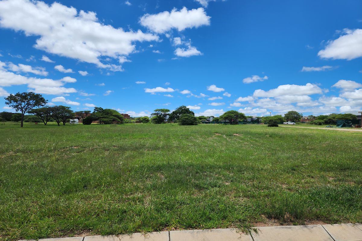 A clear, level residential vacant land plot featuring established grass and mature trees, ready for development.